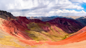 Colorful mountain range with a vibrant rainbow in the middle, showcasing the breathtaking beauty of Rainbow Mountain in Peru, Vinicunca